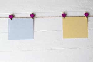 Yellow and blue memo sheets fastened with a decorative pins on a white wooden board. photo