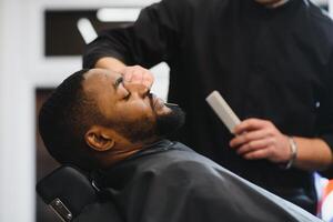 Black man in the barbershop. Cute black man makes a haircut in the African salon. Hair style. Haircut for adults. photo