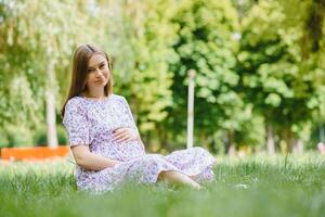 Beautiful pregnant woman relaxing in the park photo