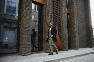 Fashion portrait of a handsome young African American business man walking outdoors in a casual pose. photo