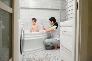 madre Lavado pequeño hijo en baño foto