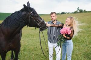 Pareja en amor teniendo divertido en naturaleza. joven Pareja con un caballo. foto