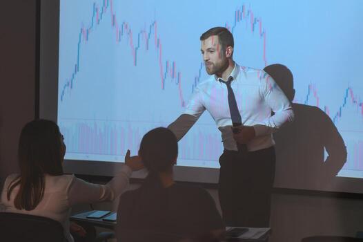 Man is standing near projector and showing graphs and business graphs. photo