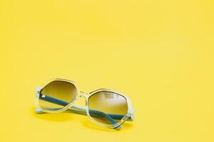 yellow sunglasses on yellow background photo