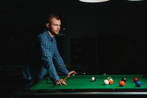 Thoughtful man plays billiards. Billiard room on the background. photo