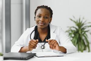 de cerca retrato de amigable, sonriente confidente hembra cuidado de la salud profesional con laboratorio abrigo, estetoscopio, brazos cruzado. aislado hospital clínica antecedentes. hora para un oficina visita. foto