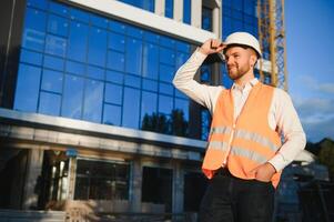 Engineer next to building cranes. Concept - large construction project. Architect directs the construction process. Drawings and tablet in the hands. photo