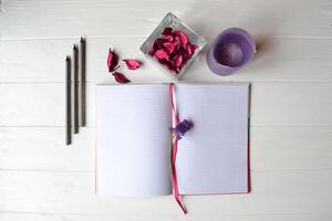 Composition with sketchbook, pencils and decoration elements on the white wooden desk. Inspirational flat lay. Background with place for text. photo