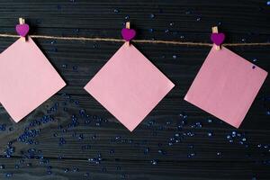 Pink memo sheets fastened with a decorative pin on a dark blue wooden board. photo