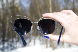 Sunglasses in female hand. Macro shot in a forest. photo