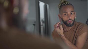 Preto brasileiro homem aplicando faço acima olhando às a espelho video