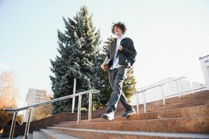 retrato de un contento masculino estudiante en pie en instalaciones con bolso foto