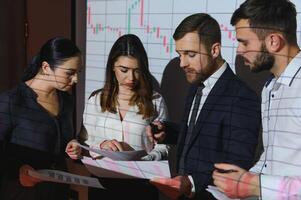 Group of business people working at modern office.Technical price graph, red and blue candlestick chart and stock trading computer screen background. Double exposure. Traders analyzing data photo