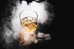 whiskey with ice on black background with smoke photo