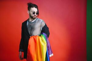 Gay man hold rainbow striped flag isolated on colored background studio portrait. People lifestyle fashion lgbtq concept photo