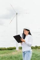 Female engineer holding a blueprints at wind farm photo