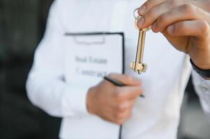 Male Realtor Standing Outside Residential Property Holding Keys photo