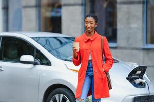 Wondering about new technology. Woman on the electric cars charge station at daytime. photo