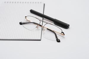 Blank diary, pen, and glasses on white background photo