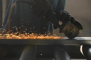 Primer plano de trabajador cortar metal con molinillo. chispas al moler hierro. baja profundidad de foco foto