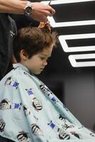 Cheerful Caucasian boy getting hairstyle in barbershop. photo