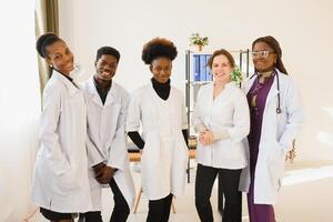 Multiracial team of doctors in a hospital standing in a corridor ready to make a ward round. photo