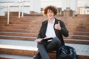 emocionado estudiante teniendo descanso Entre clases cerca universidad, sonriente a cámara al aire libre foto