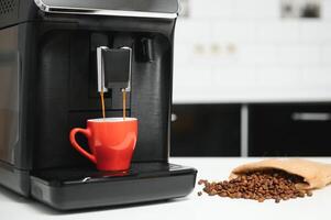 blurred background of kitchen and coffee machine with red cup and space for you photo