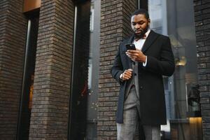 Moda retrato de un hermoso joven africano americano negocio hombre caminando al aire libre en un casual pose. foto