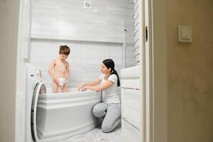 Mother washing little son in bathroom photo