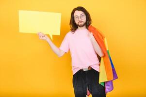 Gay man wearing bright pink top hold rainbow striped flag isolated on colored background studio portrait. People lifestyle fashion lgbtq concept photo