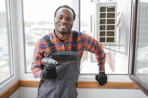 un profesional electricista hombre es fijación el pesado aire acondicionador foto