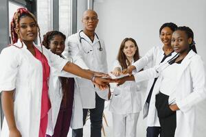 Group of doctors putting hands together in clinic. Unity concept. photo