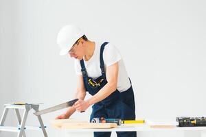 carpenter sawing white board during apartment renovating photo