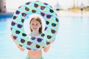 el concepto de recreación a mar. el niña sostiene un inflable circulo para nadando por el piscina foto