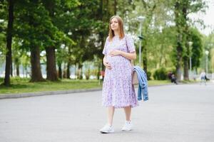 The pregnant girl on walk in city park photo