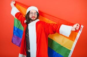 gay hombre vestido como Papa Noel claus participación un multicolor bandera foto