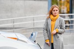 Woman near a rental electric car. Vehicle charged at the charging station. photo