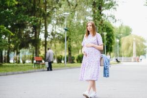 Beautiful pregnant woman relaxing in the park photo