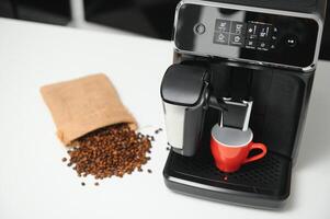 Modern espresso coffee machine with a cup in interior of kitchen closeup photo