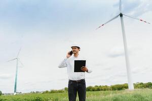 Windmill engineer talking on the phone on windmill and sky background. A man in a helmet supervises the operation of the electric windmills. photo