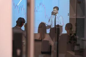 Man is standing near projector and showing graphs and business graphs. photo