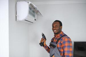 Young African Male Technician Repairing Air Conditioner photo