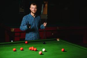 Young man playing billiards in the dark billiard club photo