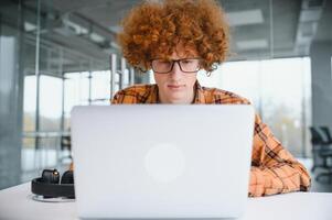 masculino programador vestir gafas para ojos proteccion mientras trabajando en Lanza libre vía ordenador portátil computadora, inteligente estudiante acecho tutorial en netbook foto