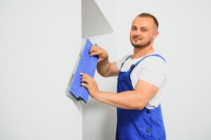 un hombre procesos el pared con un espátula. yesero a trabajar. foto