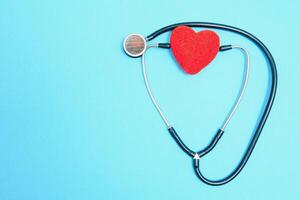 Global healthcare concept.Stylish doctor with heart on blue background.Close-up of red heart and stethoscope on a blue background. Listen to the heart with statoscope photo