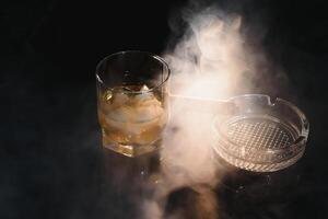 vaso de frío whisky con cigarro en oscuro antecedentes foto