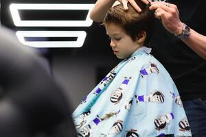 alegre caucásico chico consiguiendo peinado en barbería foto
