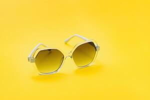 yellow sunglasses on yellow background photo